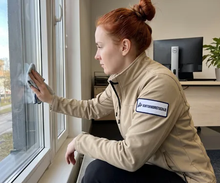 A cleaner in a beige jacket with a logo squats and wipes the office window with a cloth, a label with the drying time is left on each cleaned chair.