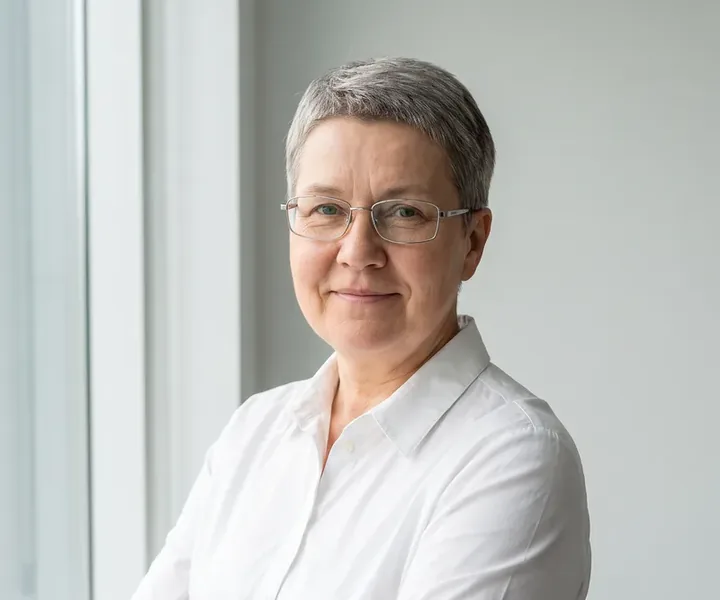 Site manager Sirje Pedaja with short gray hair, glasses and a white collared shirt in front of the window, the site supervisor gives the alarm code to the cleaner only on the spot, not on the phone.