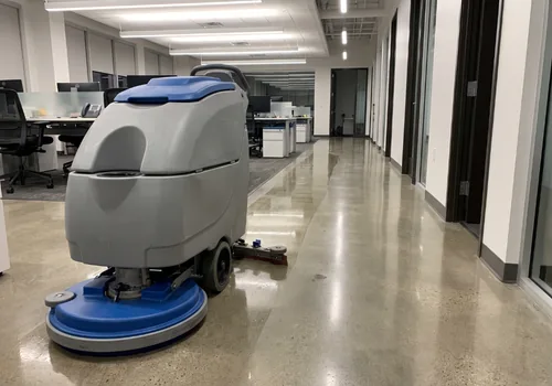 A scrubber-dryer on a shiny polished concrete floor in an office corridor, for polished concrete the scrubber-dryer has its own suction nozzle that is not used on any other type of floor.